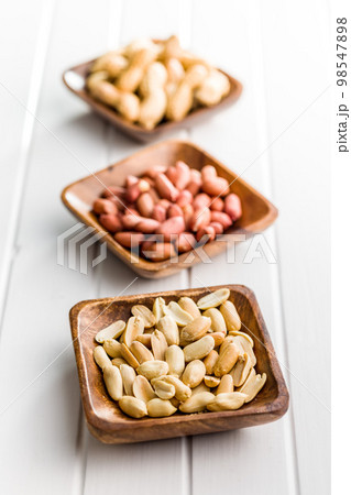 Unpeeled and peeled peanuts in bowl on kitchen table. Unpeeled and peeled peanuts in bowl on kitchen table. 98547898