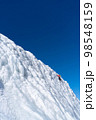 A climber in a red suit climbs an icy white mountain 98548159