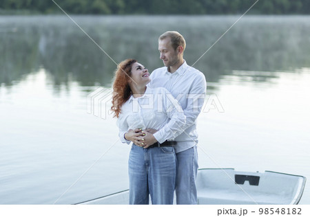 Romantic Caucasian man hugs Latin woman, couple enjoys time standing in boat, sailing in water, look at each other. Happy smiling lovers wear casual clothes. Celebrating St Valentine Day, fairy date Romantic Caucasian man hugs Latin woman, couple enjoys time standing in boat, sailing in water, look at each other. Happy smiling lovers wear casual clothes. Celebrating St Valentine Day, fairy date 98548182