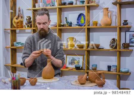 Professional male potter making ceramic jug 98548497