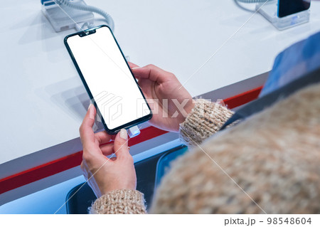 Mock up: woman looking at smartphone with blank white screen at store, shop 98548604