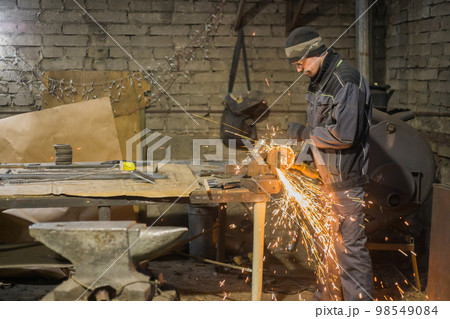Blacksmith sawing metal with hand circular saw Blacksmith sawing metal with hand circular saw 98549084