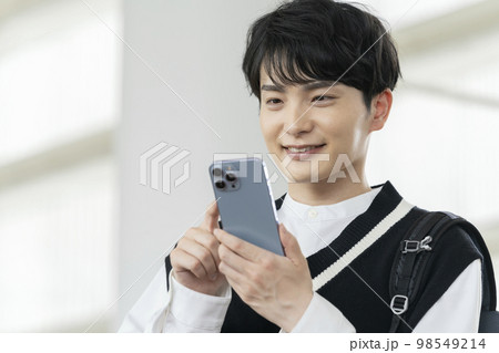 スマートフォンを持った笑顔の若い男性 スマートフォンを持った笑顔の若い男性 98549214