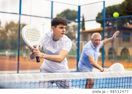 Male player ready to hits the ball while playing padel on hard court Male player ready to hits the ball while playing padel on hard court 98552477
