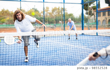 Caucasian man playing paddle tennis on padel court Caucasian man playing paddle tennis on padel court 98552528