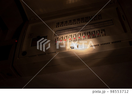 暗い部屋の中で分電盤のブレーカーを調べる 98553712