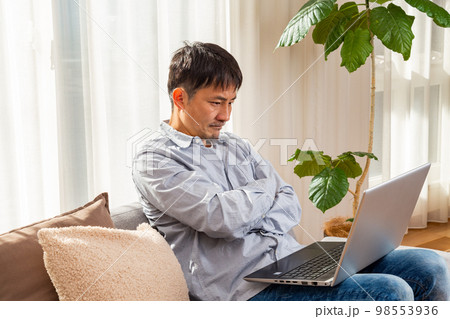 リビングでパソコン作業をする男性 リビングでパソコン作業をする男性 98553936