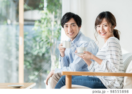 リビングで寛ぐ若い夫婦 98555898