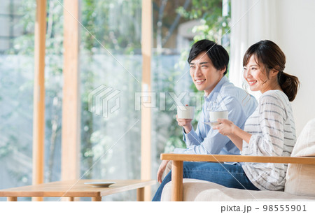 リビングで寛ぐ若い夫婦 リビングで寛ぐ若い夫婦 98555901