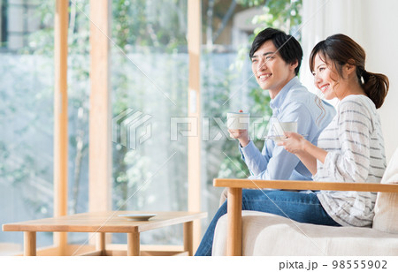リビングで寛ぐ若い夫婦 リビングで寛ぐ若い夫婦 98555902