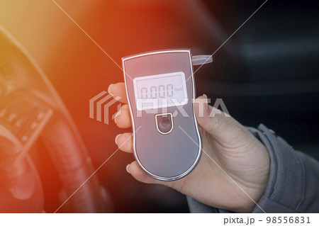 a woman with a breathalyzer in the car, testing for alcohol  98556831