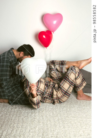 A couple of lovers hold a large balloon in the shape of a heart. The concept of Valentine's Day. Front view. A couple of lovers hold a large balloon in the shape of a heart. The concept of Valentine's Day. Front view. 98558582