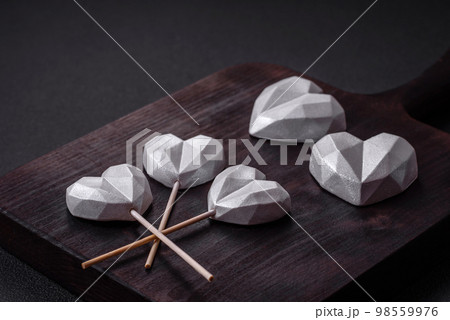 Beautiful tasty sweet candies in gray color on a dark concrete background Beautiful tasty sweet candies in gray color on a dark concrete background 98559976