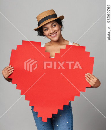 Mixed race african american caucasian girl in straw hat holding big paper pixel style heart shape with copy space for text 98560766