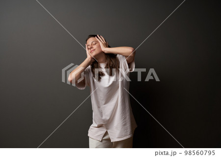 Casual girl with closed eyes holding her head in hands 98560795