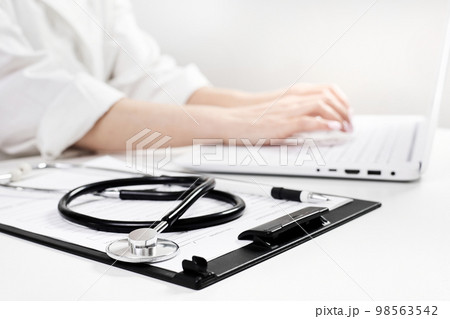 Phonendoscope or stethoscope on the background of a doctor who works on a laptop 98563542