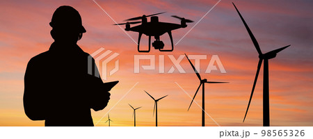 Silhouette of engineer with tablet computer, drone and wind turbines 98565326