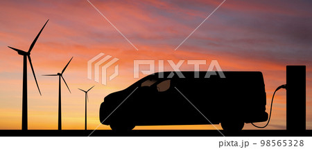 Silhouette of electric van with charging station and wind turbines 98565328