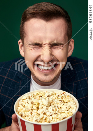 Young caucasian man in 3d glasses eating popcorn 98565344