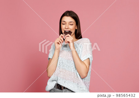woman in sweater biting sweet chocolate bar 98565432