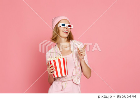 woman in t-shirt and hat with popcorn pointing at the copy space woman in t-shirt and hat with popcorn pointing at the copy space 98565444