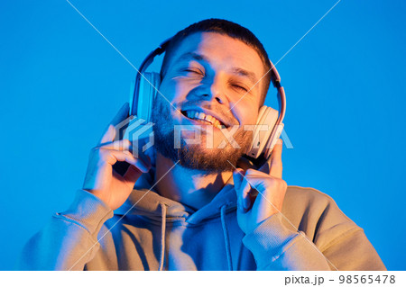 man with headphones in sweatshirt enjoying favorite music 98565478