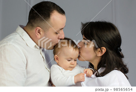 young happy parents kiss their little baby 98565654