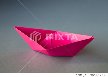 Pink paper boat origami isolated on a grey background Pink paper boat origami isolated on a grey background 98565735