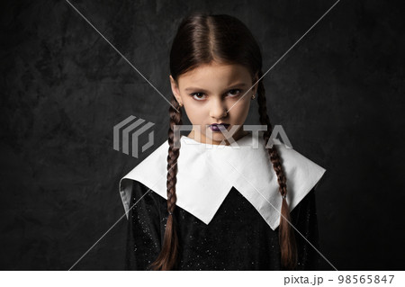 A sullen girl with pigtails in a black dress with a white collar 98565847