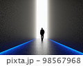 The silhouette of a man walking towards a bright light in the opened huge wall. A light in the end of a tunnel. The concept of success, freedom of choice, open mind, meditation. 98567968