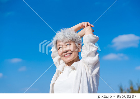 青空の下でストレッチをするシニアの女性 98568287