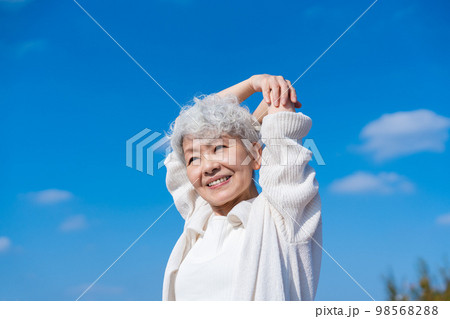 青空の下でストレッチをするシニアの女性 98568288