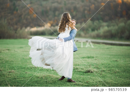 Wedding couple on the nature is hugging each other. Beautiful model girl in white dress. Man in suit Wedding couple on the nature is hugging each other. Beautiful model girl in white dress. Man in suit 98570539