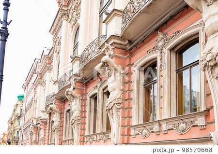 Facade of pink color historic house with beautiful windows, sculptures of Atlant, Atlas or Titan. Male man sculpture with beard 98570668