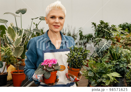 Woman holding succulent plant. Woman in a greenhouse holds a pot Woman holding succulent plant. Woman in a greenhouse holds a pot 98571625