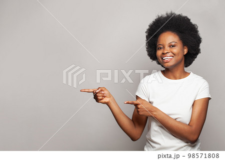 Happy nice brunette woman pointing finger on white studio wall banner background with copy space Happy nice brunette woman pointing finger on white studio wall banner background with copy space 98571808