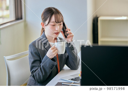 デスクで電話をする若い女性 98571998