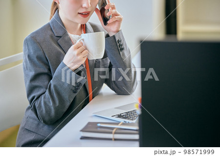 デスクで電話をする若い女性 デスクで電話をする若い女性 98571999