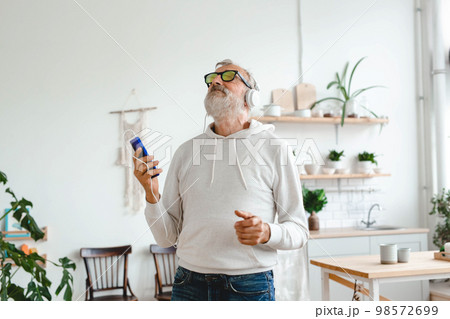 Happy senior man dancing while listening to music with headphones - active old people and enjoyment dance mood Happy senior man dancing while listening to music with headphones - active old people and enjoyment dance mood 98572699