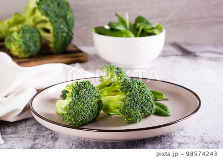 Fresh broccoli divided into inflorescences on a plate on the table. Vegetable diet. Fresh broccoli divided into inflorescences on a plate on the table. Vegetable diet. 98574243