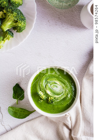 Bowl with broccoli cream soup on the table. Healthy food. Top and vertical view Bowl with broccoli cream soup on the table. Healthy food. Top and vertical view 98574264