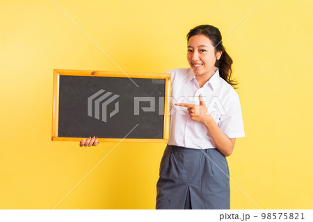 girl in uniform holding blackboard beside her with finger pointing girl in uniform holding blackboard beside her with finger pointing 98575821