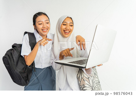 two smiling vocational high school girls while using a laptop 98576043