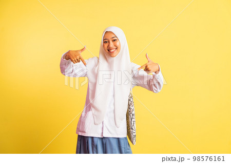 happy veiled student girl with two fingers pointing down happy veiled student girl with two fingers pointing down 98576161