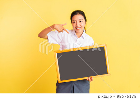 girl in high school uniform holding blackboard with pointing finger 98576178