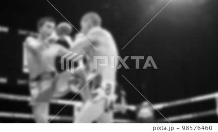 Blurred images black and white photo style of Thai boxing or Muay Thai or Kickboxing which local and foriegn boxer are fighting on the ring at indoor stage as martial art sport. Muay Thai Kick boxing 98576460