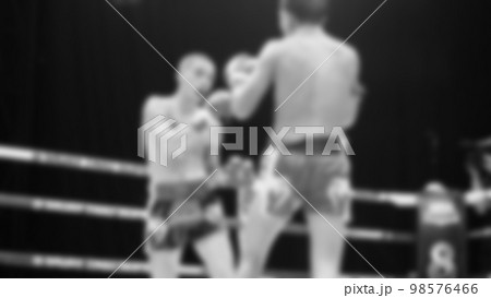 Blurred images black and white photo style of Thai boxing or Muay Thai or Kickboxing which local and foriegn boxer are fighting on the ring at indoor stage as martial art sport. Muay Thai Kick boxing 98576466