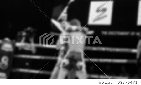 Blurred images black and white photo style of Thai boxing or Muay Thai or Kickboxing which local and foriegn boxer are fighting on the ring at indoor stage as martial art sport. Muay Thai Kick boxing 98576471