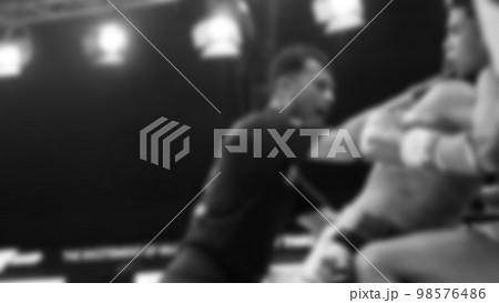 Blurred images black and white photo style of Thai boxing or Muay Thai or Kickboxing which local and foriegn boxer are fighting on the ring at indoor stage as martial art sport. Muay Thai Kick boxing 98576486