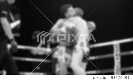 Blurred images black and white photo style of Thai boxing or Muay Thai or Kickboxing which local and foriegn boxer are fighting on the ring at indoor stage as martial art sport. Muay Thai Kick boxing 98576491